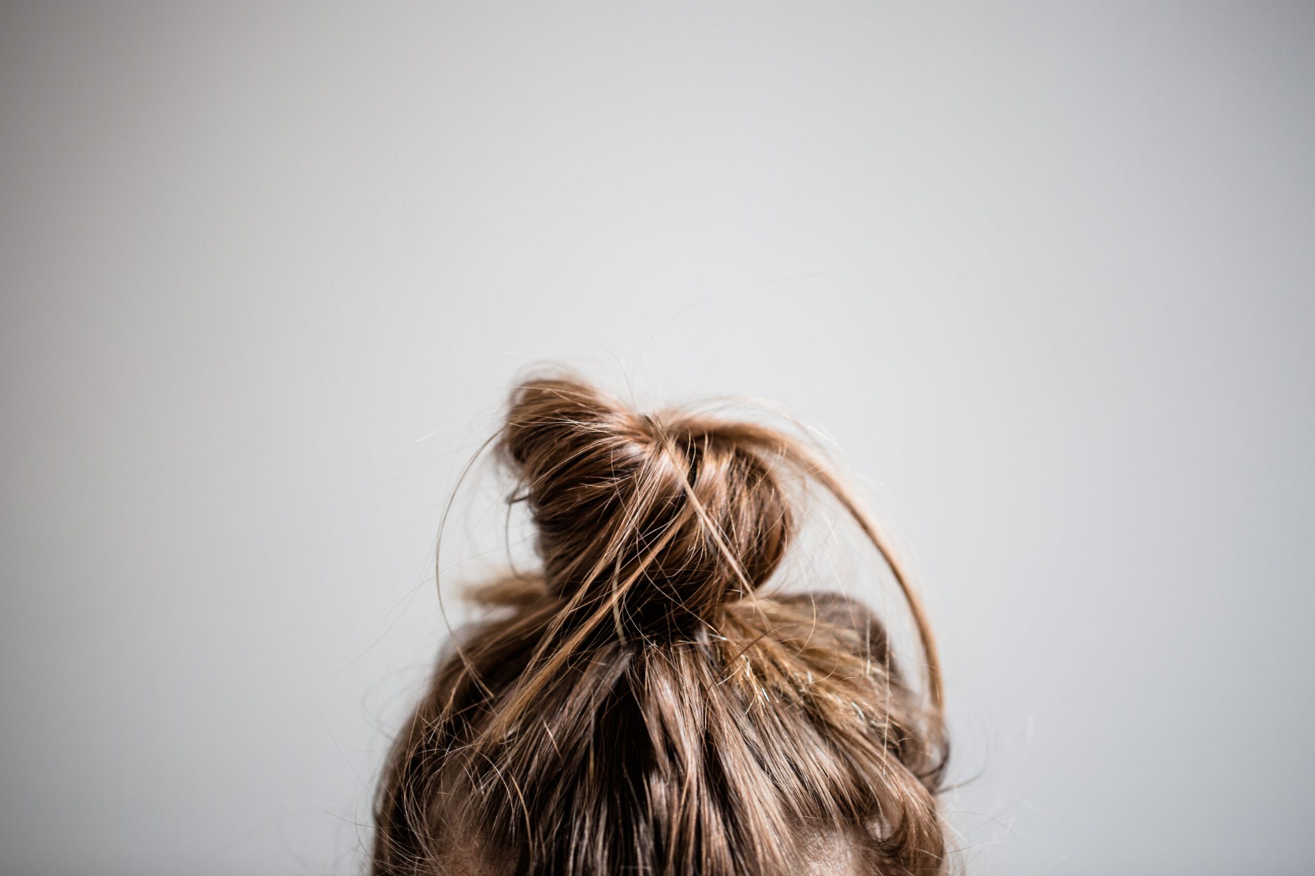 Long dirty blonde hair tied into a bun with a white background.