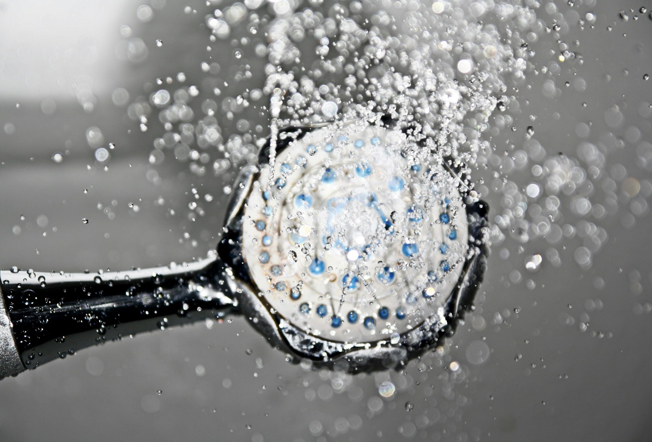 A black shower head with water splashing out of it.